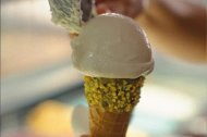 Delicia artesanal: helado cremoso servido en cono con borde de pistache.