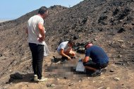 Un agente de la Guardia Civil, recogiendo restos óseos un mes y medio después del incendio en presencia del hijo de una de las víctimas y el alcalde de Bédar.