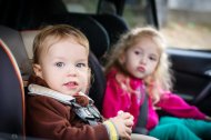 Niños en un coche con sillita.