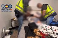 Agentes de la Policía Nacional inspeccionan una habitación durante el registro de la vivienda.