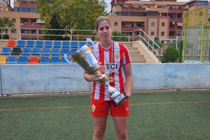 Blanca Plaza exhibiendo un trofeo y una medalla.
