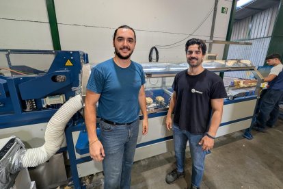 Javier y Jesús junto a la máquina de envases en funcionamiento.