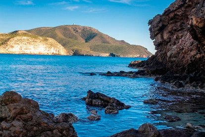 Las rocas de origen volcánico emergen del agua azul en la Playa Negra