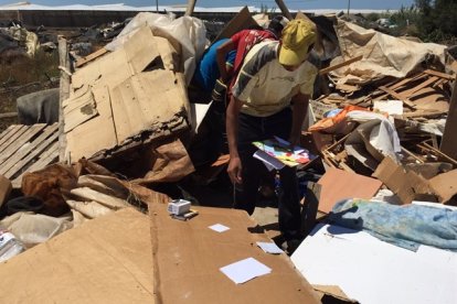 Un inmigrante busca sus enseres entre los restos de las chabolas derruidas en el asentamiento de