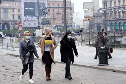 Tres jóvenes caminan por Milán, dos de ellas con mascarillas.