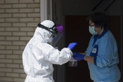 Un sanitario entrega las pruebas a otro, tras realizar una recogida de muestra desde el coche para detectar casos de coronavirus
