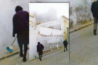 Una mujer barriendo la acera de su casa en la calle Santa María de la Alcazaba.