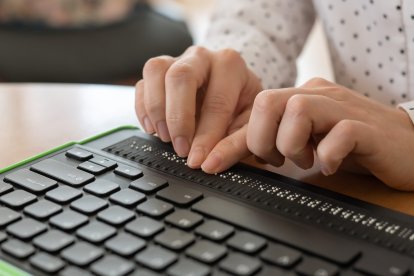 Una persona ciega leyendo una noticia en braile