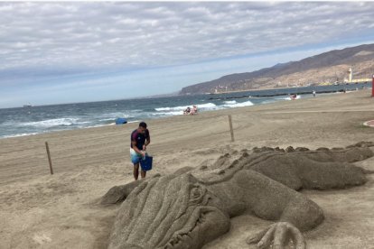 Karim refrescando a su caimán, ya desaparecido,, sobre la arena de la playa de El Zapillo.
