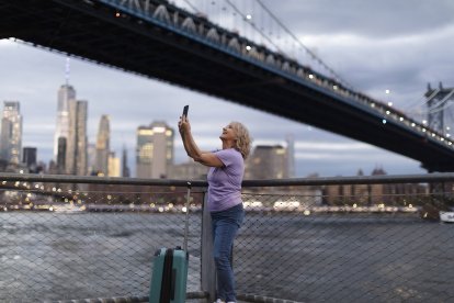 Una viajera inmortaliza el skyline de Nueva York al atardecer, bajo el puente de Brooklyn.