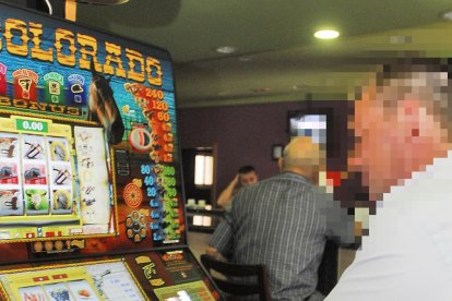 Un usuario jugando a una maquina tragaperras en un bar.