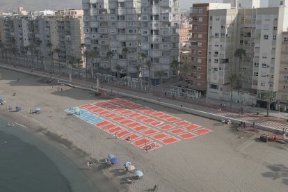 Casi 50 toallas gigantes dibujan un aparcamiento de 1.500 metros cuadrados en El Zapillo.