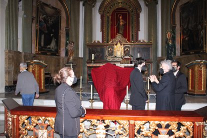 La hermana mayor del Santo Sepulcro y el párroco de San Pedro junto al Cristo Crucificado velado.