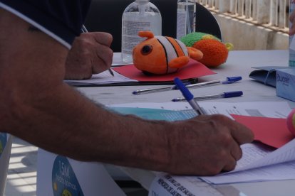 Detalle de un hombre firmando con un peluche de Nemo en la mesa