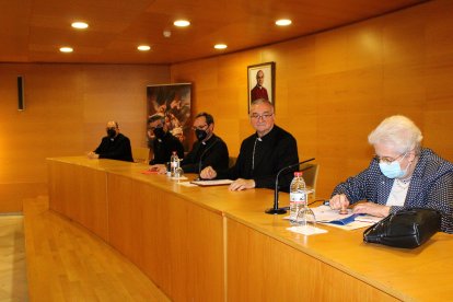 La canciller saliente firmando ante el obispo coadjutor.