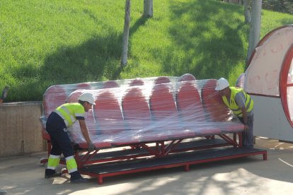 Los trabajadores descargando los banquillos en el Estadio.