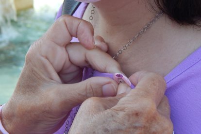 Socia de la la Asociación de Mujeres Mastectomizadas de Almería (AMAMA) regalando un lazo rosa por el día mundial