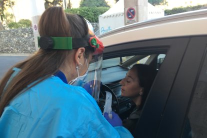 Una sanitaria realiza una PCR a través de la ventanilla de un coche.