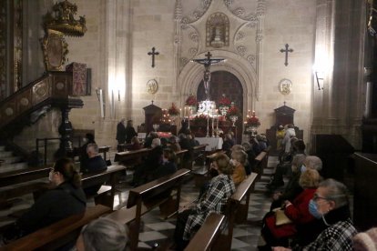 Fieles esperando el comienzo de la eucaristía con la imagen del Cristo de la Escucha ante la puerta del claustro.