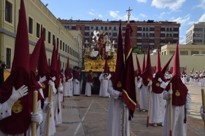 Fila de nazarenos preparados para salir a la calle con el paso del Cristo al fondo.