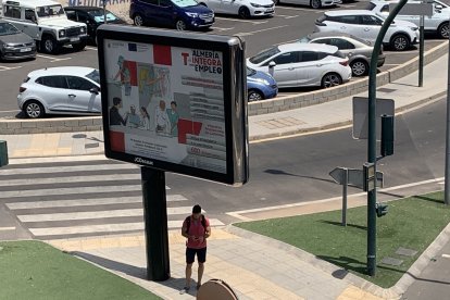 Almeriense se refugia del calor en la sombra de un cartel.