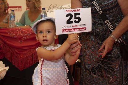 Un participante mostrando su número en el Concurso de Trajes de Flamenca y traje corto de La Voz de Almería.