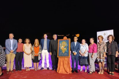 Foto de familia de hermanos mayores y miembros de la Agrupación junto al cartel.