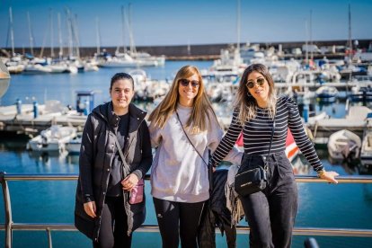Tres jóvenes con el Puerto de Roquetas de fondo.