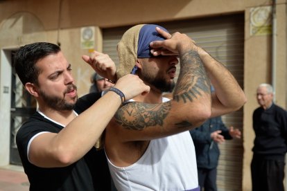 Un costalero ayuda a otro a ajustarse el costal antes del ensayo.