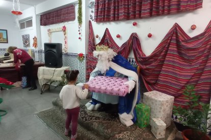 El rey Melchor entregando el regalo a una pequeña.