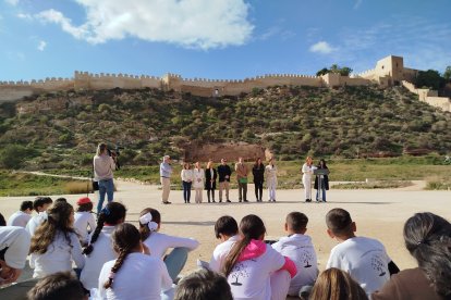 Alumnos escuchando los poemas junto a la representación institucional