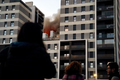Decenas de personas observan el edificio en llamas.
