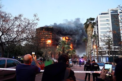 Decenas de personas observan el edificio en llamas.
