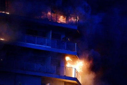 Dos personas en un balcón del edificio en llamas en el barrio de Campanar.
