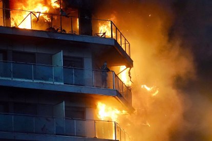 Una persona en un balcón del edificio en llamas.