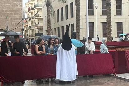Un nazareno habla con familiares y amigos en la plaza de la Catedral, tras refugiarse en el templo a causa de la lluvia.
