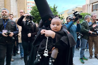 Un nazareno de luto con un bebé en brazos.