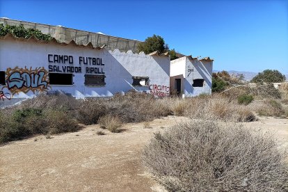 La fachada con grafitis y el acceso al bar al fondo.
