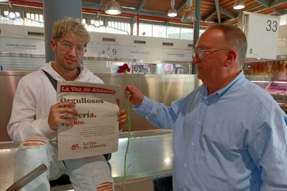 A la izquierda, Juan Antonio Muñoz recibe un periódico y una flor en el Mercado Central.