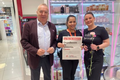 El director de LA VOZ entrega un periódico y un clavel a dos dependientas del centro de Almería.