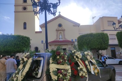 El coche fúnebre  cargado de coronas en la Plaza de la Iglesia.