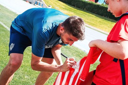 Edgar firmando una camiseta.