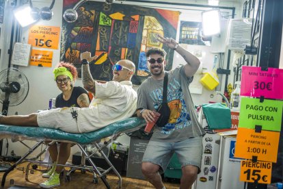 Dos amigos se hacen un tatuaje en uno de los puestos del festival.