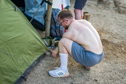 Un joven planta su tienda en la zona de la acampada.