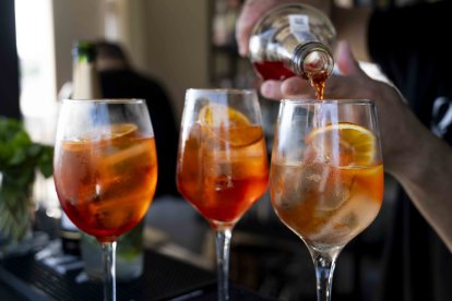 Imagen de la preparación de tres cócteles Aperol Spritz.