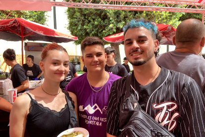 Aarón, Erik e Irene, pareja y hermano, comen migas, croquetas y hamburguesas en el ambigú de la Plaza Virgen del Mar.