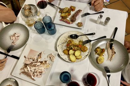 Imagen de una de la mesa con platos del menú como lecha con guarnición de patatas y lomo de vaca.