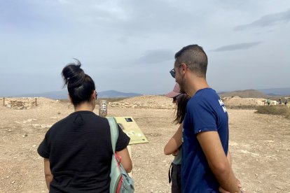 Una familia observa uno de los paneles informativos sobre la necrópolis del yacimiento.