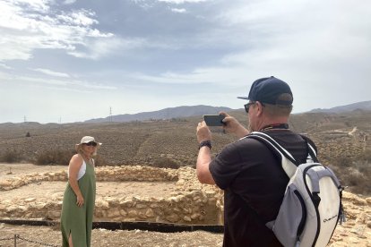 Dos turistas se hacen fotos con el taller metalúrgico de fondo.