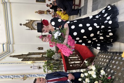 Una madre junto a su hija dejan sus flores sobre el tablón de ofrendas.